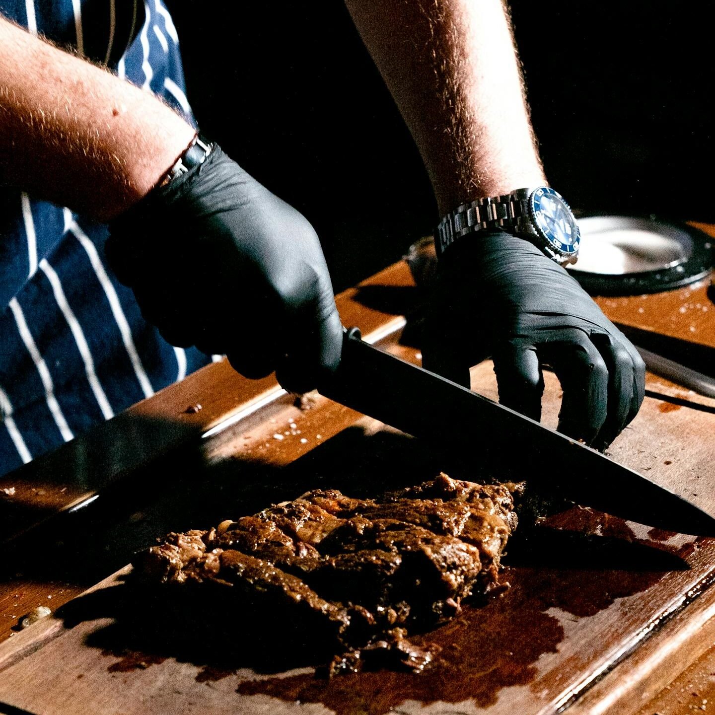 Chef slicing a juicy steak on a wooden board in a restaurant kitchen.
